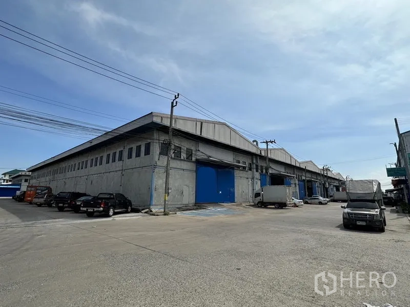 คลังสินค้า ให้เช่าในBang Phli, Samut Prakan - มุมอาคารโกดังคอนกรีตขนาดใหญ่ ประตูโหลดสินค้าโทนสีน้ำเงินและลานรถกว้าง ย่านบางพลี สมุทรปราการ