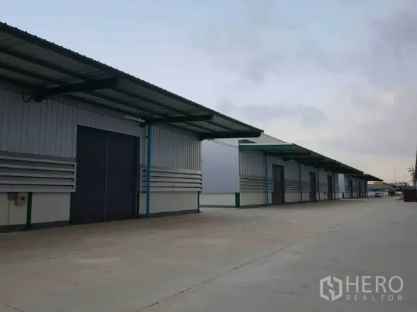 Warehouse for rent in Prawet, Bangkok - Multiple warehouse units with canopies and roller shutters facing a large maneuvering area.