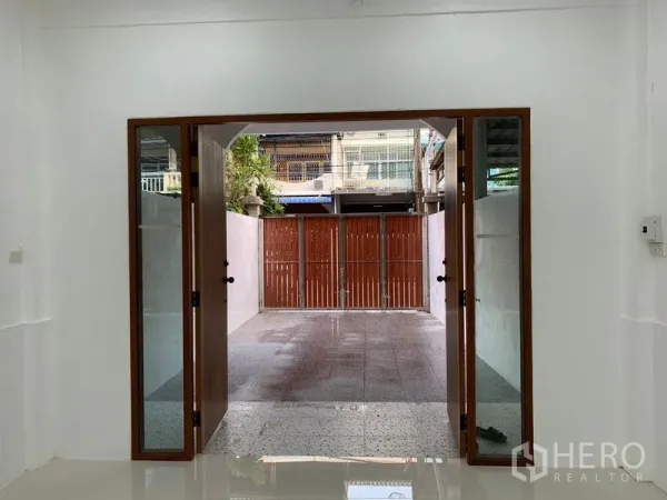 Townhouse for sale in Yan Nawa, Bangkok - Glass doors open to a tiled front patio with a wooden privacy gate.