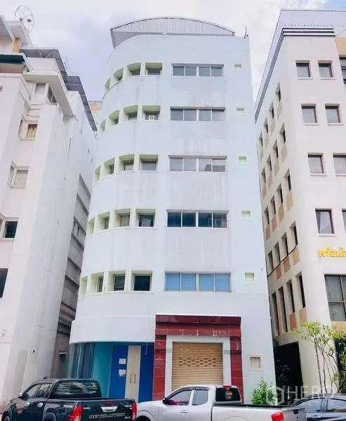 带办公室的家 出售在Huai Khwang, Bangkok - 曼谷怀宽区弧形立面的多层家用办公楼，底层卷闸门与路边停车位
