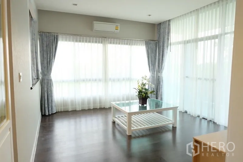 独立式住宅 出租在Prawet, Bangkok - 二楼家庭厅，转角落地窗与浅色窗帘