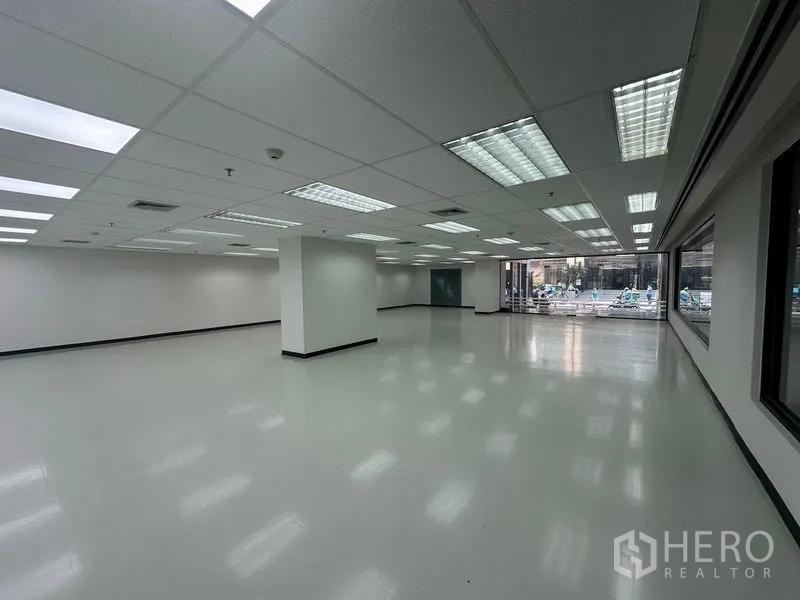 办公空间 出租在Phaya Thai, Bangkok - 开放办公区，荧光灯照明，立柱与大窗户，可眺望楼内广场。