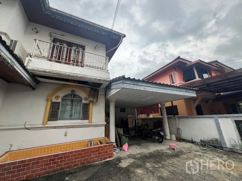 独立式住宅 出售在Phra Khanong, Bangkok - 房屋侧立面，带小阳台及有顶车位。