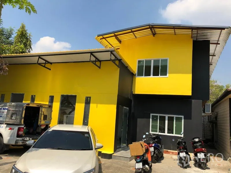 独立式住宅 出售在Khlong Toei, Bangkok - 黄黑配色的两层独栋住宅，金属屋顶，前方设有车位。