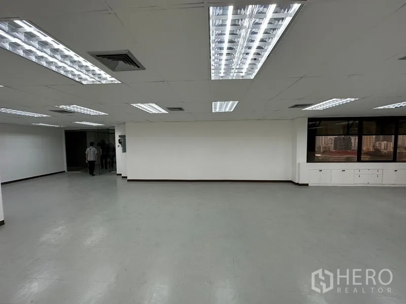 办公空间 出租在Watthana, Bangkok - 开放办公区，白色墙面、嵌入式灯光、转角窗景与内置收纳柜。