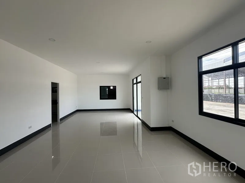Factory for rent or sale in Sai Noi, Nonthaburi - Large open-plan office with big windows overlooking the yard.