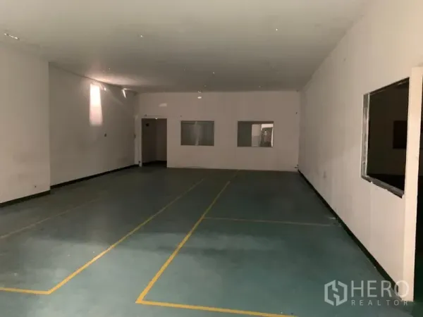 Factory for rent in Pathum Thani - Spacious workroom with marked flooring, small internal windows and access doors.