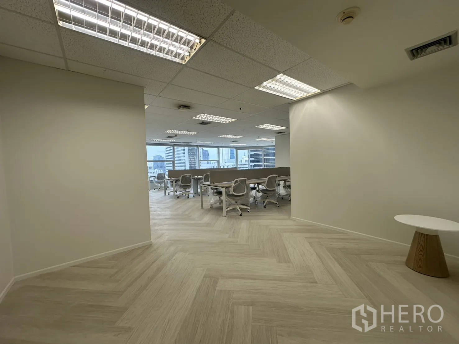 办公室 for rent in Sathon, Bangkok - 入口休息区通向开放工区，浅色人字形地板与吊顶照明。