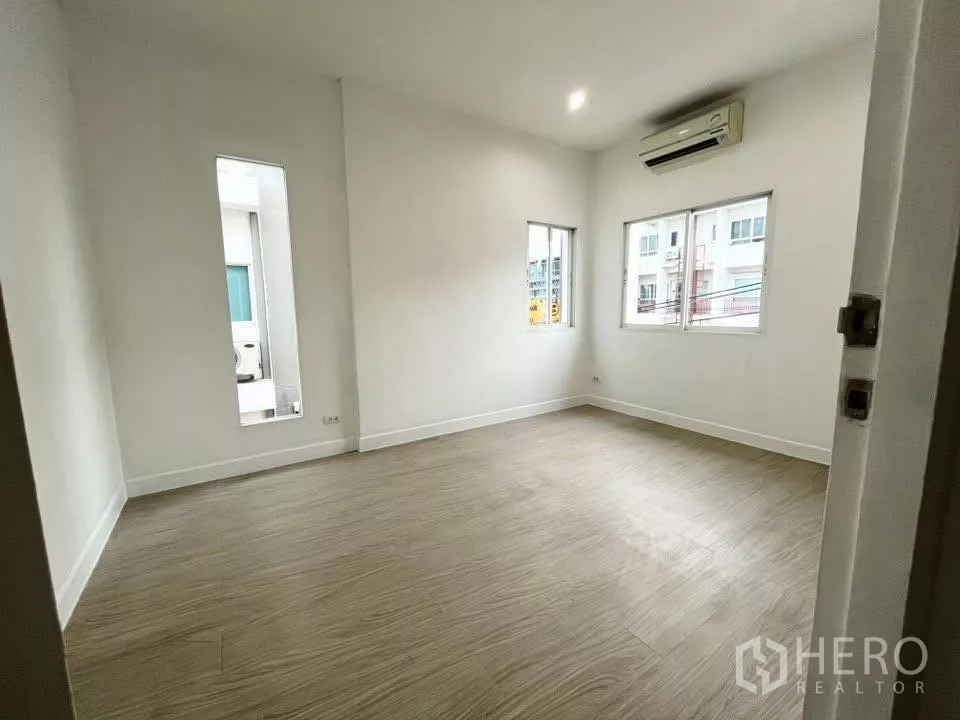 Home Office for rent in Bueng Kum, Bangkok - Bright empty room with wood-look flooring, white walls, windows and air-conditioner.