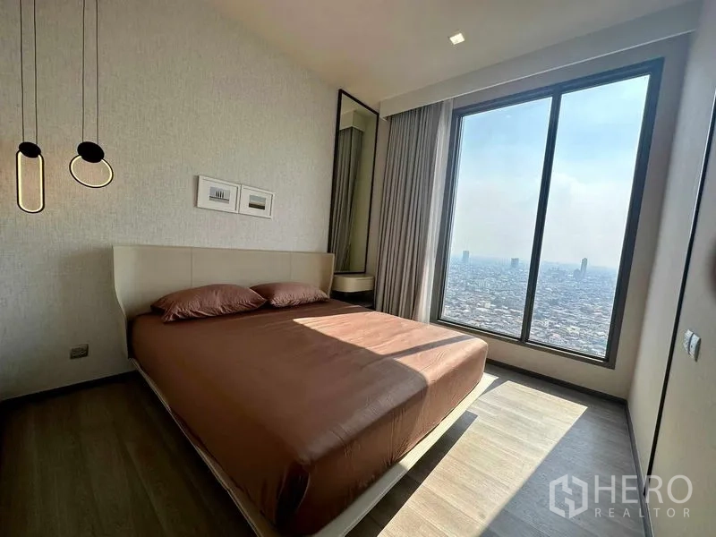 Condominium for rent in Bang Kho Laem, Bangkok - Primary bedroom with pendant lights and a wide window showcasing panoramic city views.
