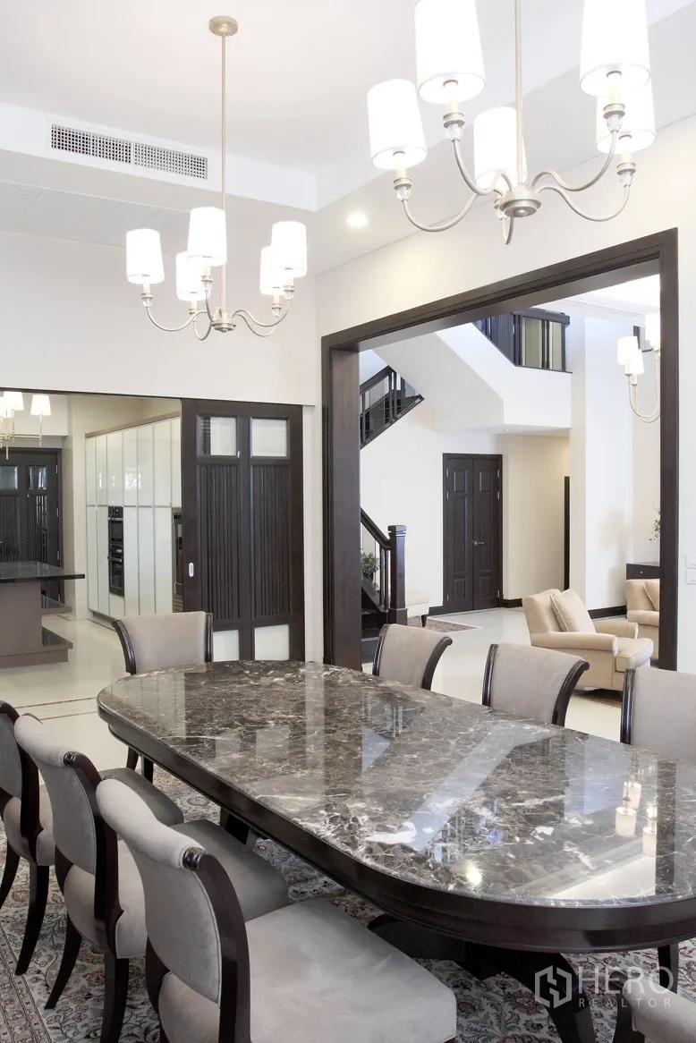 Detached House for rent in Khlong Toei, Bangkok - Elegant dining room with a marble-top table, chandeliers and a view of the staircase and lounge.