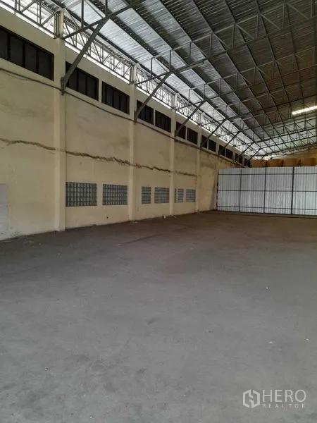 Warehouse for rent in Yan Nawa, Bangkok - Spacious warehouse interior with high steel truss roof, ventilation windows and concrete floor.