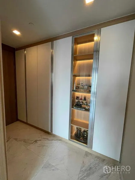 Condominium for rent or sale in Bang Rak, Bangkok - Built-in wardrobe wall with lit display shelves in the foyer.