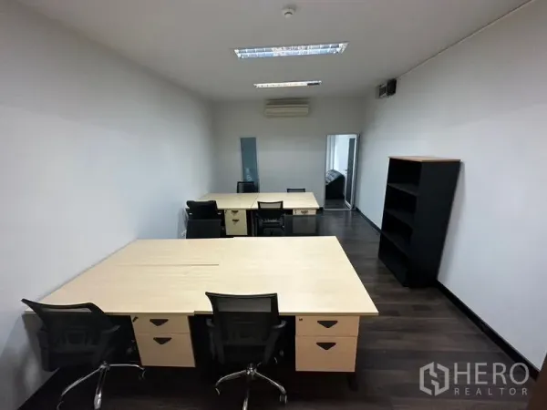 Office Space for rent in Khlong Toei, Bangkok - Open-plan workspace with multiple desks, task chairs, bookshelf and ceiling lighting on dark wood floors.