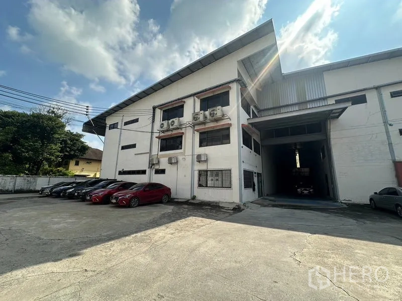 Warehouse for rent in Suan Luang, Bangkok - Entry drive, parking area, and front facade of the warehouse and office.