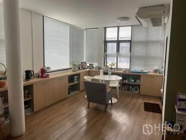 Retail Space for rent in Watthana, Bangkok - Bright upper-floor room with blinds, wood flooring, built-in cabinets and a round table.