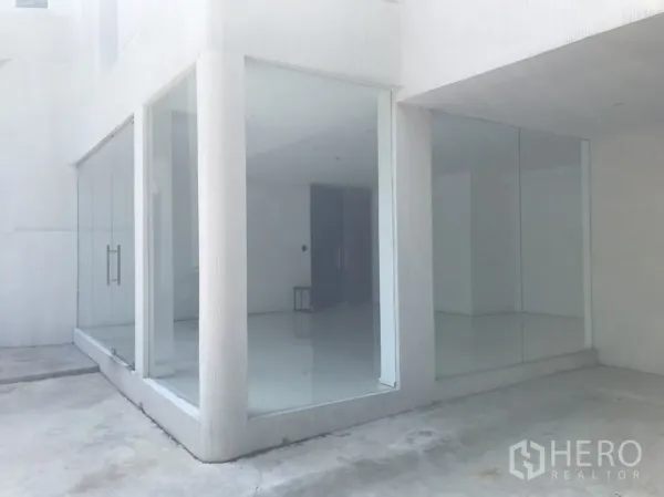 Retail Space for rent in Khlong Toei, Bangkok - Corner retail unit with floor-to-ceiling glass walls and a white ground-floor facade.