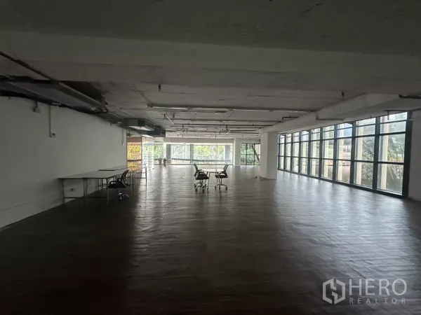 Retail Space for rent - Deep rectangular retail space with windows on two sides and wide plank flooring.