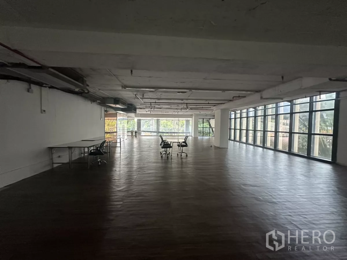 Retail Space for rent - Deep rectangular retail space with windows on two sides and wide plank flooring.