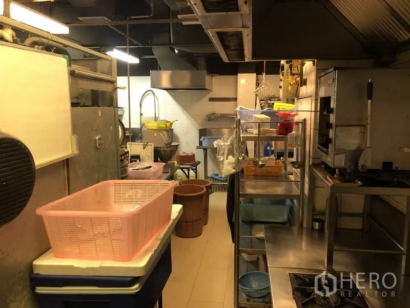 Retail Space for rent in Khlong Toei, Bangkok - Service corridor kitchen with exhaust hood, gas range, prep tables and plastic storage bins.