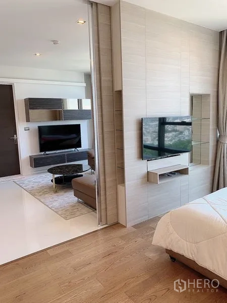 Condominium for sale - Sliding partition separates bedroom from living area with dual TVs.