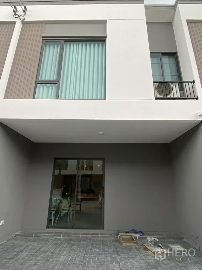联排别墅 出租在Bang Phli, Samut Prakan - 现代两层联排别墅外立面，大窗户、带顶车位与推拉玻璃门。