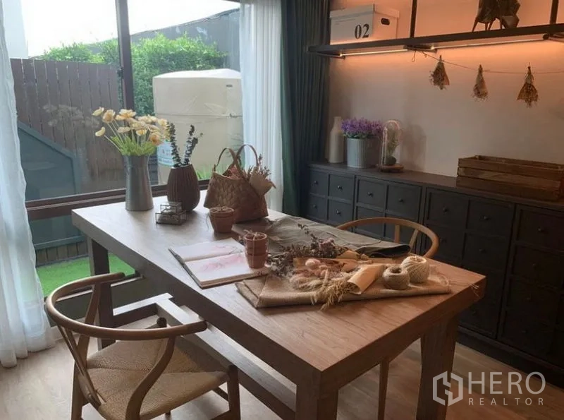Detached House for sale in Bang Kapi, Bangkok - Dining or study room with wooden table, built-in cabinets and sliding glass doors to the yard.