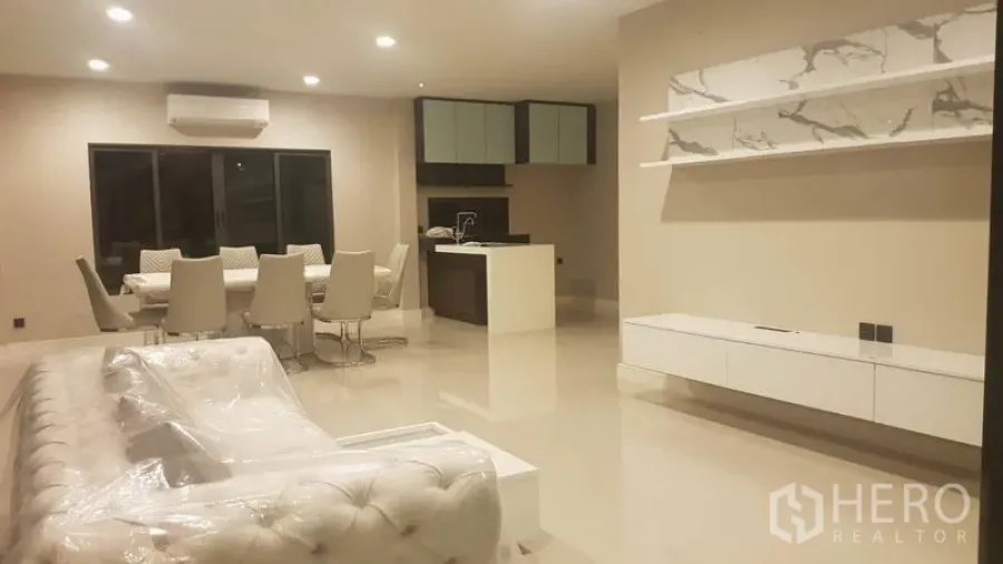 Detached House for rent in Saphan Sung, Bangkok - Open-plan living and dining area with glossy floors, a tufted sofa and a modern kitchen island.