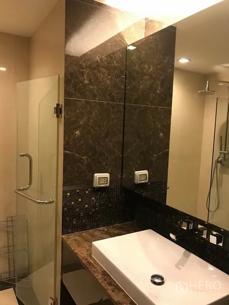 Condominium for rent in Watthana, Bangkok - Contemporary bathroom featuring a square vessel sink, marble backsplash and glass-enclosed shower.