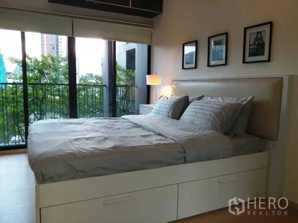 公寓 出售在Watthana, Bangkok - 卧室配落地玻璃门，连接阳台，绿树城市景观。