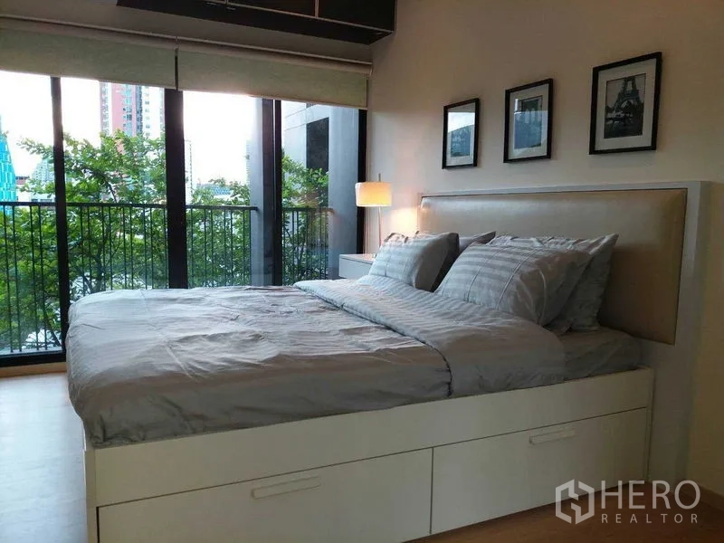 公寓 出售在Watthana, Bangkok - 卧室配落地玻璃门，连接阳台，绿树城市景观。