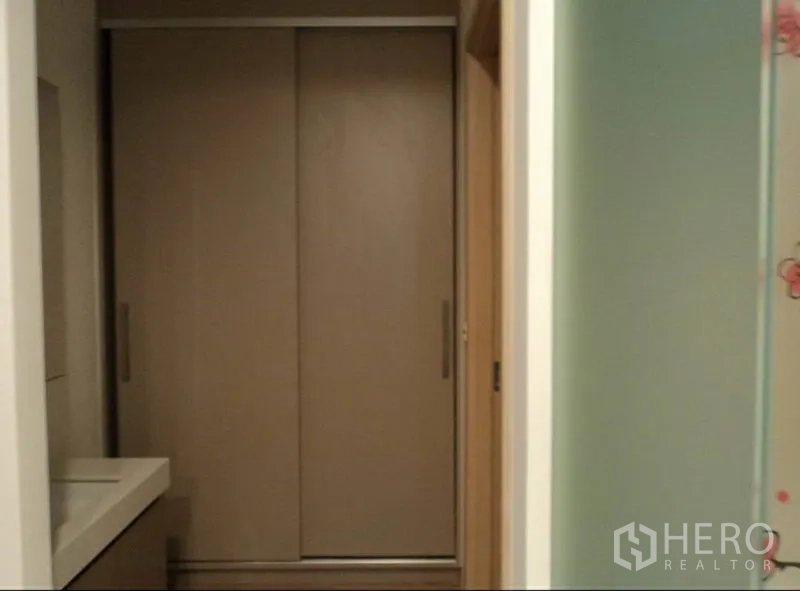 Condominium for rent in Khlong Toei, Bangkok - Hallway with sliding wardrobe doors and a vanity counter beside a glass partition.