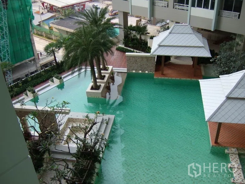 公寓 出租在Bang Kapi, Bangkok - 度假风泳池，棕榈树与凉亭环绕，景观平台相连。