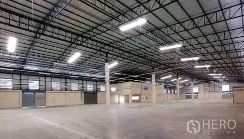 Warehouse for rent in Bang Bo, Samut Prakan - Open warehouse floor with high ceiling, columns, roller shutters and ample lighting.