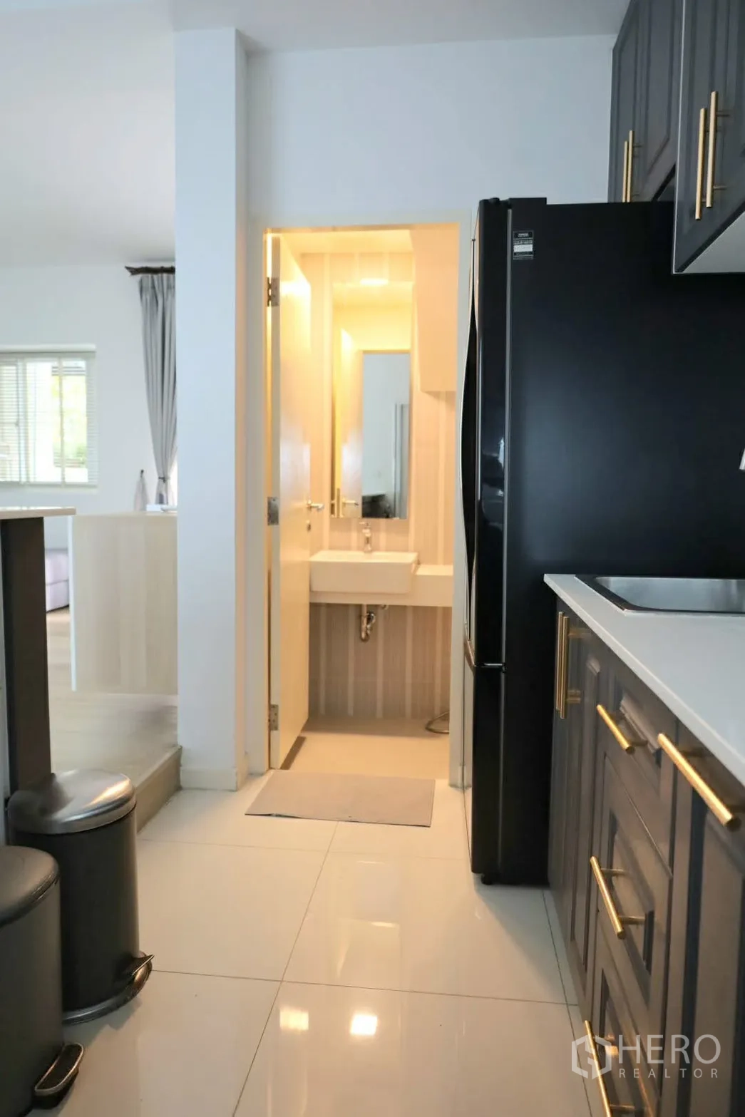 联排别墅 for rent in Prawet, Bangkok - 厨房过道可见客用卫浴、黑色冰箱与水槽区。