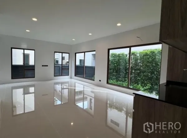 Detached House for rent in Bang Kapi, Bangkok - Spacious living room featuring large windows with views to a green hedge garden.