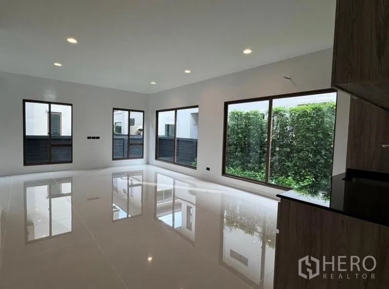 Detached House for rent in Bang Kapi, Bangkok - Spacious living room featuring large windows with views to a green hedge garden.