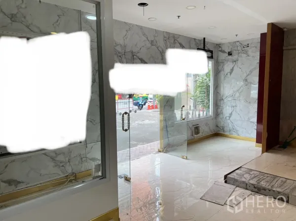 零售空间 出租在Khlong Toei, Bangkok - 店内采光明亮，大理石纹地砖、嵌入式灯光、玻璃门与临街窗。
