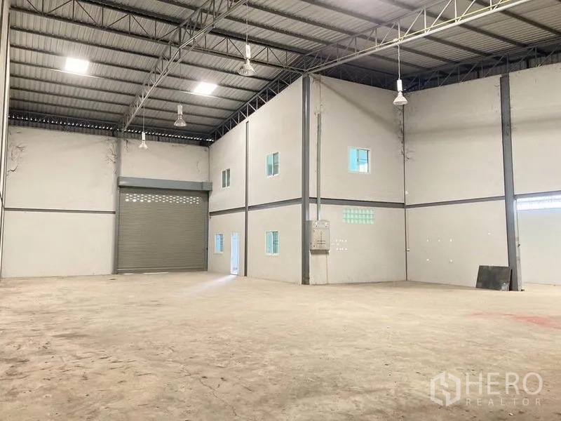 Warehouse for rent in Bang Phli, Samut Prakan - Interior view showing a two-storey office block and large roller shutter door.