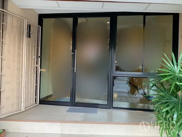 Retail Space for rent in Khlong Toei, Bangkok - Ground-floor retail entrance with frosted glass sliding doors, a small tiled step, and potted plants.