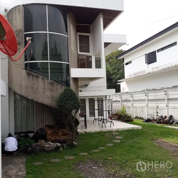 独立式住宅 出租在Khlong Toei, Bangkok - 现代白色独栋住宅，弧形玻璃楼梯间与露台，前方草坪，位于Phra Khanong。