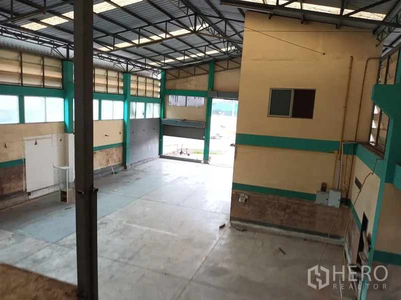 Warehouse for rent in Phasi Charoen, Bangkok - View from mezzanine over open floor and wide roller shutter loading entrance.