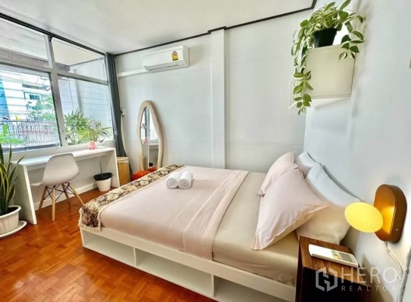 联排别墅 出租在Watthana, Bangkok - 明亮卧室，落地窗边书桌、空调与绿植