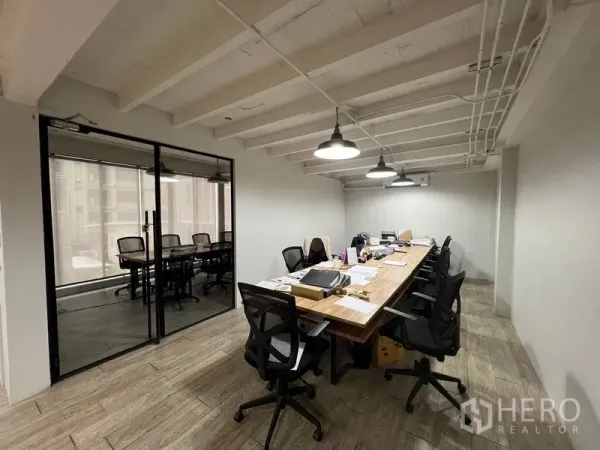 Office Space for rent in Pathum Wan, Bangkok - Work area with a long collaborative table, task chairs and an adjacent glass-walled meeting room.