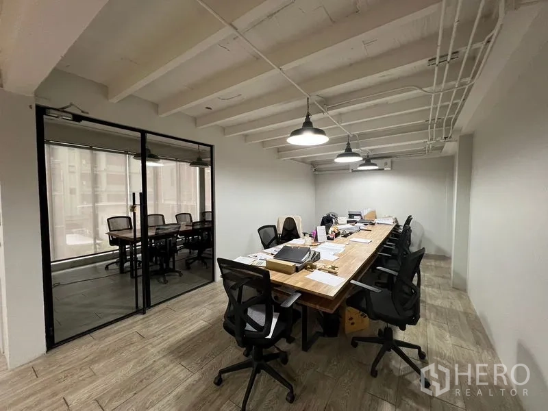 Office Space for rent in Pathum Wan, Bangkok - Work area with a long collaborative table, task chairs and an adjacent glass-walled meeting room.
