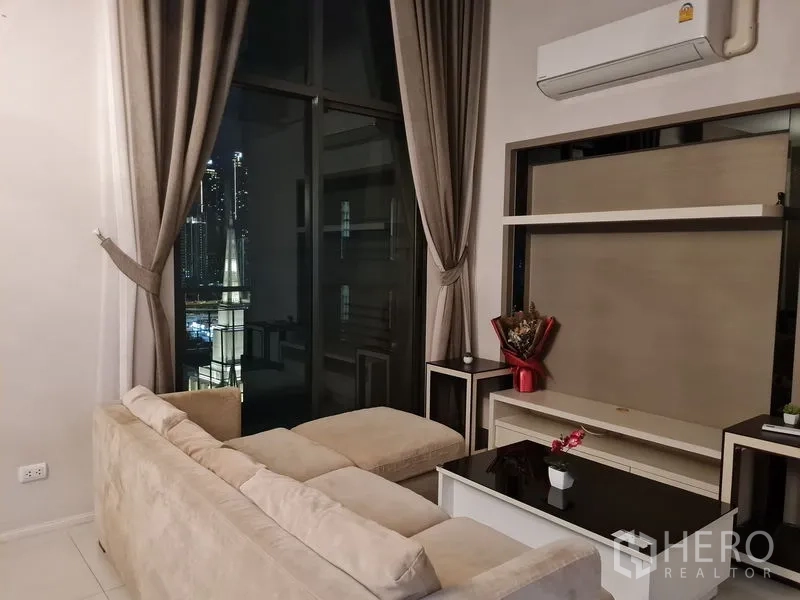 公寓 出售在Ratchathewi, Bangkok - 夜间客厅，长窗帘与壁柜，透过整面玻璃观赏城市灯光