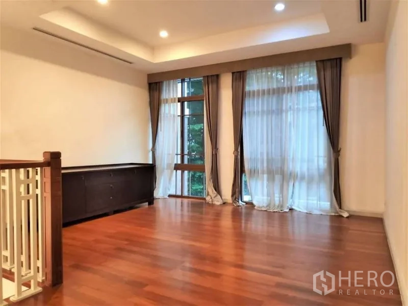独立式住宅 出租在Watthana, Bangkok - 二层起居区，大窗与轻纱窗帘，木地板通透明亮。