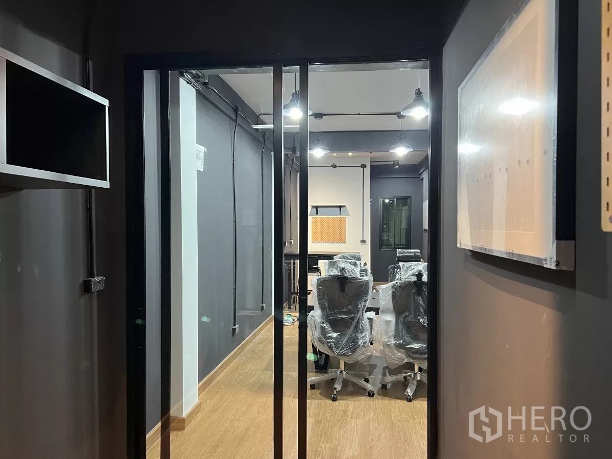 带办公室的家 出租在Pom Prap Sattru Phai, Bangkok - 玻璃门入口可见工业风办公区，木纹地板与吊灯照明。
