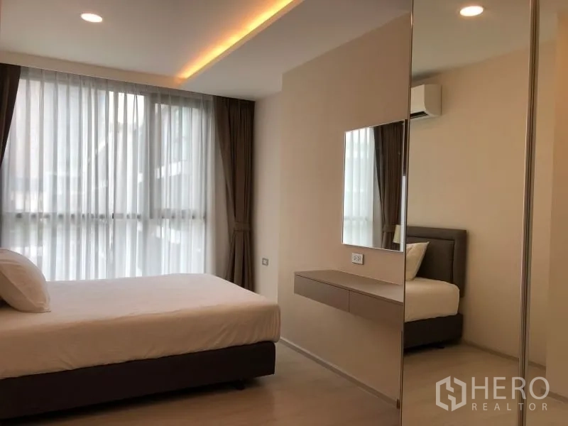 Condominium for sale in Khlong Toei, Bangkok - Second bedroom with large windows, mirrored wardrobe and floating desk.