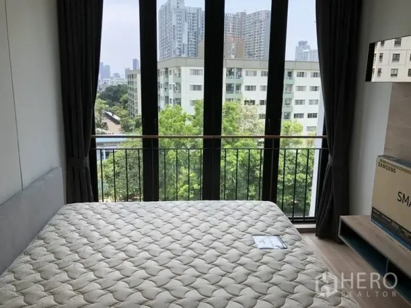 公寓 出租在Watthana, Bangkok - 主卧室配落地窗，俯瞰绿意与运河及城市楼景。